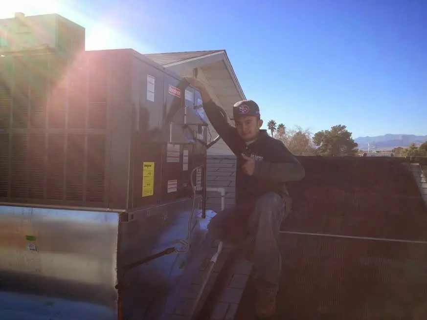 HVAC technician performing Air Duct Cleaning on a rooftop unit in Abilene